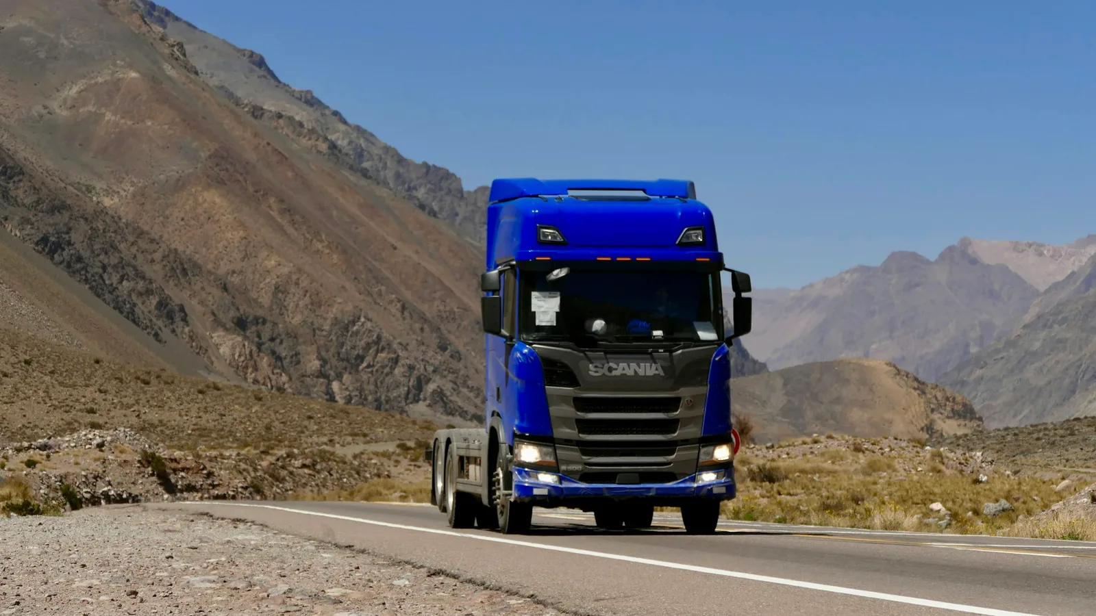 European heavy goods vehicle hauling on a mountain highway, representing Torqen's commercial vehicle friction systems
